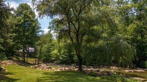 Surrounded by lush trees and a serene stream, this peaceful oasis invites relaxation.