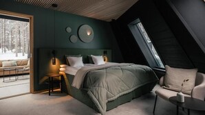 A modern bedroom with a large bed, a chair, and a small table. - Glass Resort (Rovaniemi)