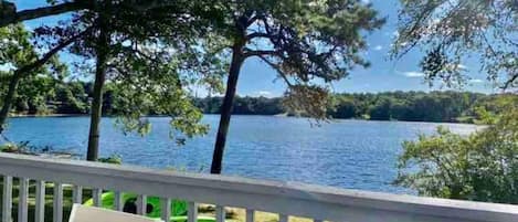 A deck with a view of a lake and trees.
