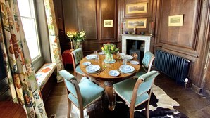 Une salle à manger élégante, avec une table ronde, des chaises, une cheminée et des tableaux encadrés accrochés aux murs.
