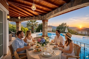 Un espace repas avec vue sur la piscine, des piliers en pierre et un plafond en bois.