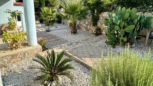 A courtyard with a stone wall, various plants, and a view of a hillside. - Stunning Villa Sana Perfect Condition, Private 100 m³ Pool & 1000m2 Garden WIFI (Muğla)