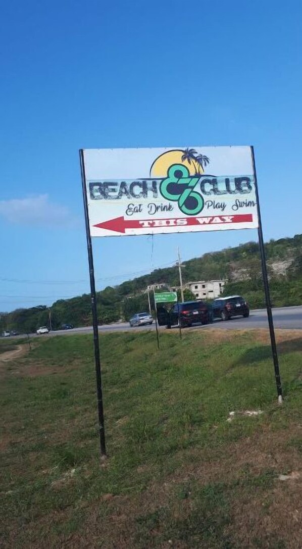A beach and club sign with a sun, palm trees, and the words "Eat Drink Play Swim".