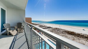 A balcony with a view of a beach and a pool.