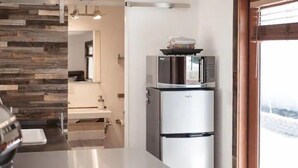 Una cocina moderna con refrigerador y microondas de acero inoxidable, un muro decorativo de madera y vista al exterior.