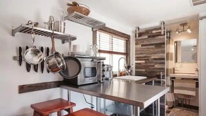 Una cocina moderna con electrodomésticos de acero inoxidable, taburetes de madera y un horno empotrado.