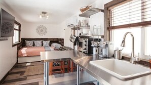 Cocina compacta con una isla central, horno empotrado y un amplio ventanal con persianas.