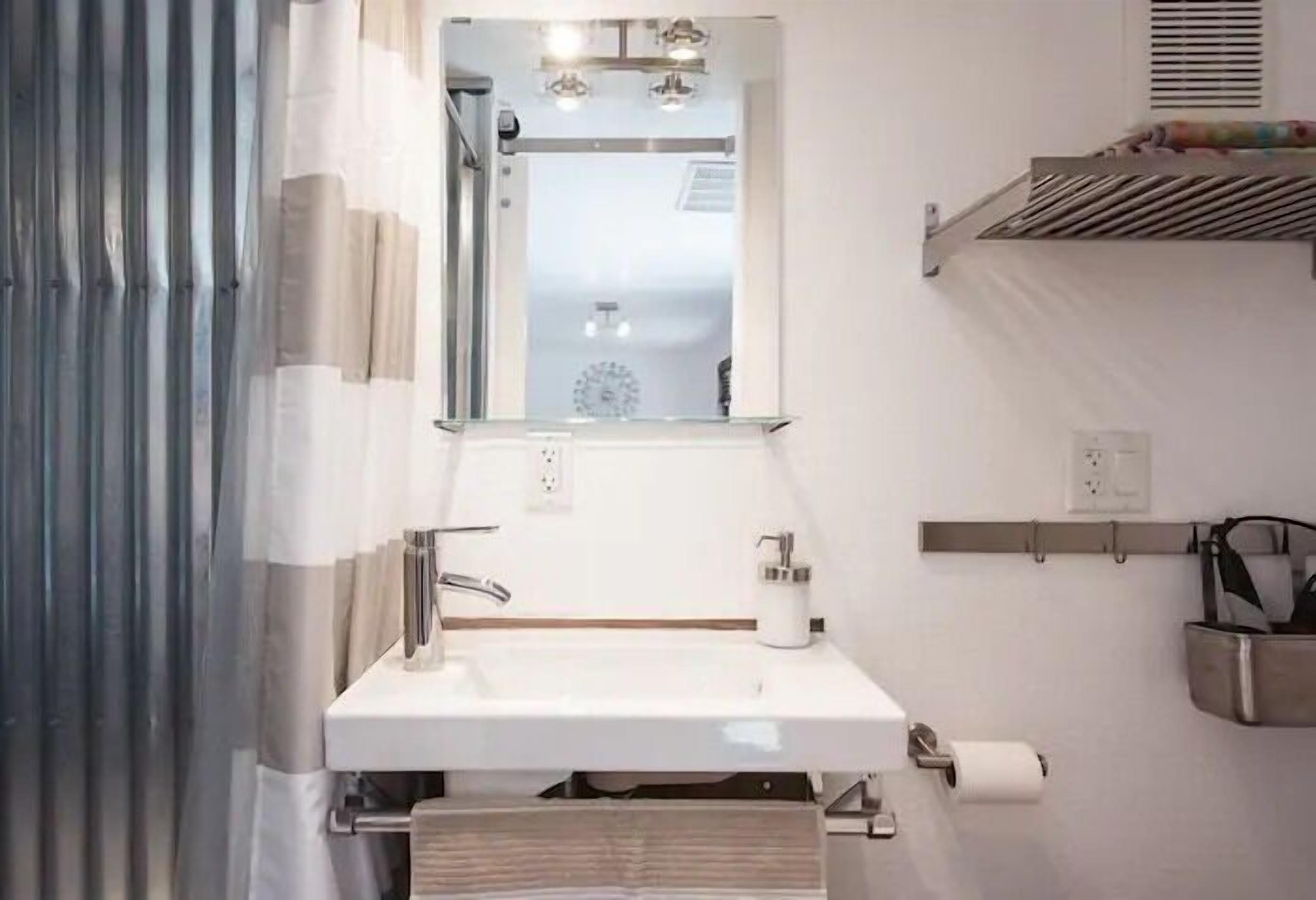 Ein modernes Badezimmer mit Waschbecken, Spiegel, Handtuchhalter und Toilettenpapierhalter.