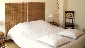 A bedroom with a large bed, a wooden chair, a small table with a lamp, and a wall-mounted picture. - SPACIOUS GITE FOR 4 PEOPLE IN AUTHENTIC PROVENCAL FARMHOUSE (Suzette)
