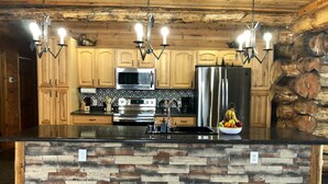 Una cocina moderna con armarios de madera, un refrigerador de acero inoxidable, un horno empotrado e isla de piedra.
