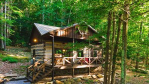 A rustic cabin with a wooden deck, stone steps, and a porch. - The Wilderness Lodge at Four Fillies Lodge w/ Hot Tub (Peterstown)
