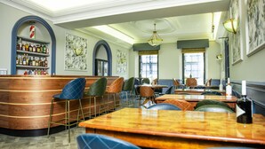 A restaurant interior with wooden tables and chairs, a bar area with shelves of bottles, and framed artwork on the walls. - The Woodside Hotel, Aberdour. Exclusive Use (Burntisland)