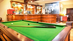 A pool table with balls and cues, a bar area with bottles and a cash register, and a billiard table in a room with wooden paneling and a ceiling light. - The Woodside Hotel, Aberdour. Exclusive Use (Burntisland)