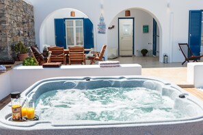 Relax in a serene outdoor oasis with a hot tub at its center, surrounded by comfortable seating and lush greenery.