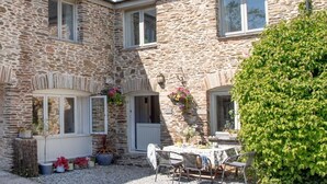 A stone building with a courtyard, a table with chairs, and potted plants. - Spacious,  Well Equipped Cottage Near South  Devon coast - Sleeps 10 (plus2) (Slapton, Near Kingsbridge)