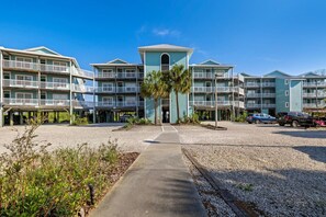 Un hôtel à plusieurs étages, doté d’une tour centrale, de nombreux balcons et d’un parking où sont stationnées plusieurs voitures.