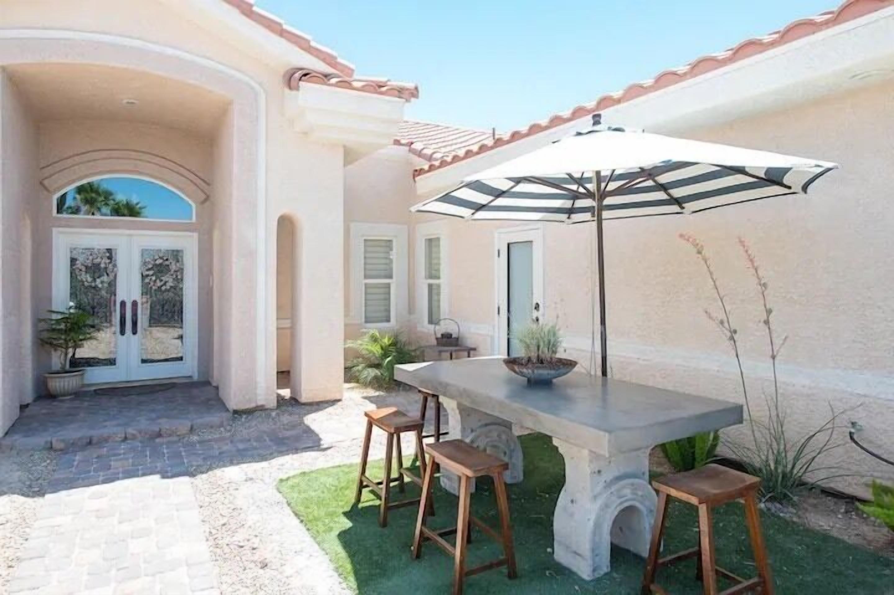Eine Terrasse mit Tisch, Stühlen, einem Blumentopf und einer Tür mit dekorativem Bogen.