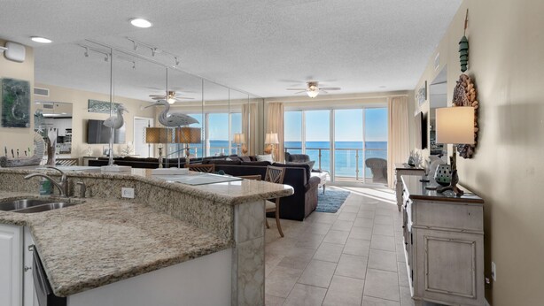 A spacious living area with a large window overlooking the ocean, a kitchen with granite countertops, and a dining area with a view.