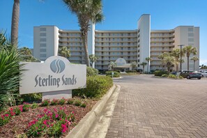 A hotel entrance with a sign reading "Sterling Sands" and a parking area in front.