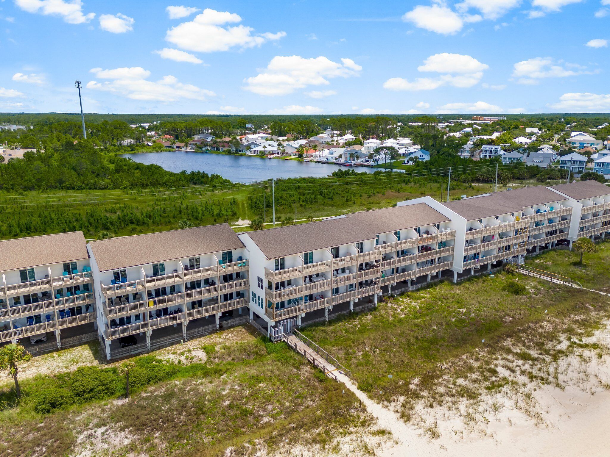 A multi-story hotel with balconies, located near a body of water and surrounded by greenery.
