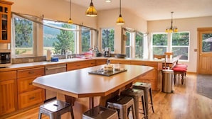 A spacious kitchen with a large island, wooden cabinets, and pendant lighting.