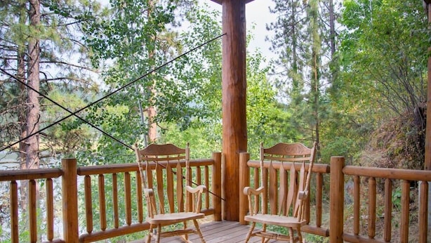 A wooden deck with two rocking chairs and a wooden railing.