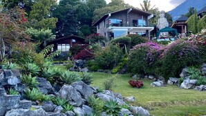 Ein zweistöckiges Haus mit einer Steinfassade, umgeben von einem gepflegten Garten mit verschiedenen Pflanzen und Steinen.