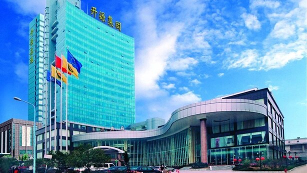 Un hôtel moderne doté d’une façade bleue en verre remarquable et d’une entrée en verre incurvée.