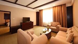 Une chambre d’hôtel dotée d’un espace salon comprenant deux canapés, une table basse, un téléviseur et un petit meuble.