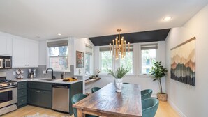A modern kitchen with dark cabinets, a wooden dining table, and teal chairs. - Tri-level condo, close to Coonskin Lift! (Telluride)