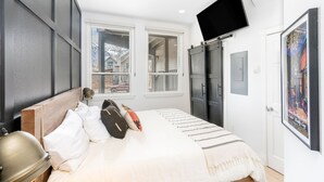 A bedroom with a bed, a TV, a window, and a door. - Tri-level condo, close to Coonskin Lift! (Telluride)