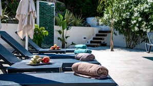 A poolside area with lounge chairs, towels, and fruit.
