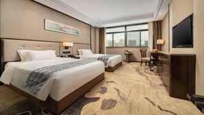 A hotel room with two beds, a television, a desk with a chair, and a large window offering a city view. - Nanning Guiwanyi Hotel (Beihu South Road Subway Station) (Nanning)