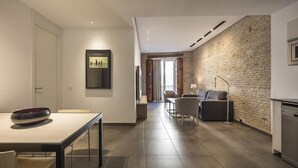 Una sala de estar moderna con comedor, pared de acento de ladrillo y televisor de pantalla plana montado en la pared.