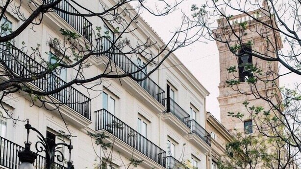 Un edificio de varios pisos con balcones, una farola y un letrero que dice 'Vicentino'.