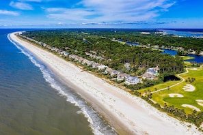 Vue aérienne d’une zone résidentielle côtière, avec des propriétés situées en bord de mer, un terrain de golf et un lac.