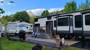 Un véhicule récréatif doté d’un patio couvert, de coins salon extérieurs et d’un barbecue.