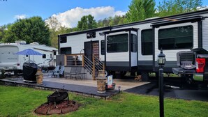 Une maison mobile dotée d’un patio, d’un espace salon extérieur et d’un barbecue.