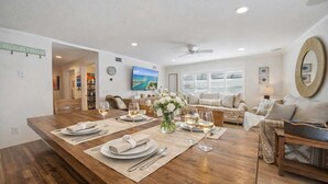 A dining area with a wooden table set for four, a vase of flowers, and a television in the background. - Siesta KeyVillage heated pool (Siesta Key)
