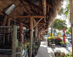 A rustic wooden structure with a thatched roof, potted plants, and a sign for 'The Coroner'. - Siesta KeyVillage heated pool (Siesta Key)