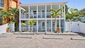 A two-story building with a balcony on each floor, surrounded by a white fence and palm trees. - Siesta KeyVillage heated pool (Siesta Key)