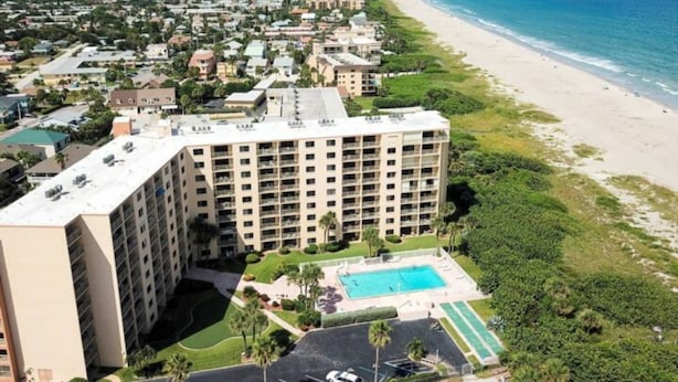 Un hotel de gran altura con varias plantas, una piscina y vistas a la playa.