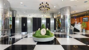 A lobby with a checkered floor, a reception desk, and a green seating area with a clock. - Ana Hotels Europa Eforie Nord (Eforie)