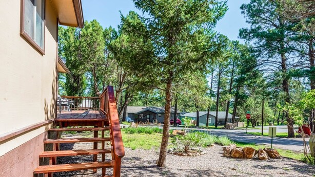Una escalera de madera que lleva a un porche con vista a una zona residencial y árboles.