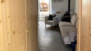 A wooden interior with a sofa, a chair, a table, and a wall-mounted light fixture. - Baleal Waterfront (Ferrel)