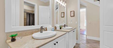 A bathroom with two sinks, a large mirror, and a vanity cabinet.