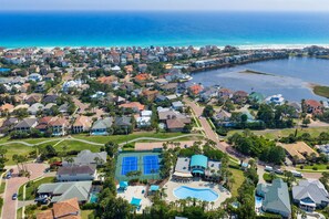 An aerial view of a residential area with houses, a swimming pool, tennis courts, and a large body of water. - Anchor Down |WOW!!! FLASH DEAL 7/18-7/25!! 1 PM Check In! | Lakefront Luxury in Destiny East with Gulf Views & Private Pool! | Clubhouse Amenities! Pickleball, Gym & Hot Tub! (Destin)