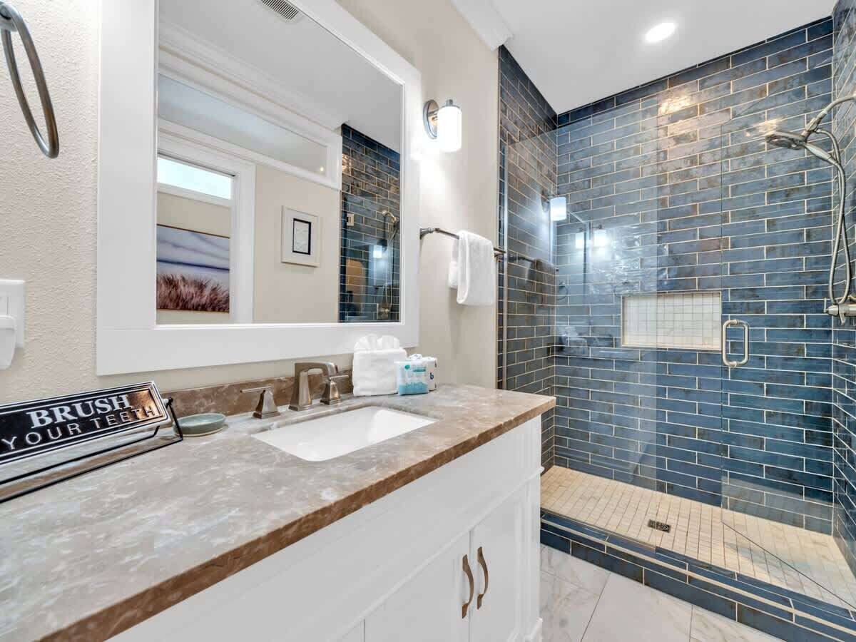 A bathroom with a sink, mirror, and shower.