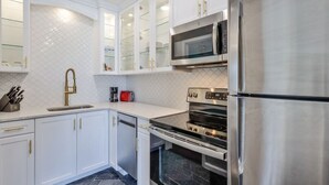A modern kitchen with white cabinets, a stainless steel refrigerator, a built-in oven, and a microwave. - 2 Bedroom Kitchen Suite#203/204 (New Smyrna Beach)