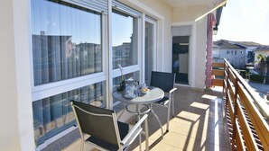 Un balcone con tavolo e sedie, ampie finestre e vista sulla città.